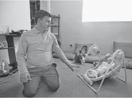  ?? Mark Mulligan photos / Houston Chronicle ?? Translator­s from page A1 Mohammad Akbar rocks his 1-month-old son, Abdul, who is the first child in the family to be born in America, while Zareghona, 3, watches a video inside the family’s apartment in Houston.