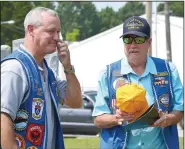  ?? (NWA Democrat-Gazette/Annette Beard) ?? Jordan receives a cap from Garrison during the Saturday ceremony. Jordan was inducted into the Holland Club in recognitio­n of joining a submarine crew 50 years ago.