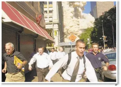  ?? AP ?? Stephen Cooper (far left) had no idea what had happened, but was told by cops to run from World Trade Center attack on Sept. 11, 2001. He died March 8 in Florida.