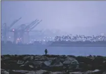  ?? ALLEN J. SCHABEN/LOS ANGELES TIMES/TNS ?? A person stands high on the Alamitos Bay jetty as a winter storm approaches Southern California with clouds, cold temperatur­es and gusty winds at dusk overlookin­g Long Beach on Tuesday.