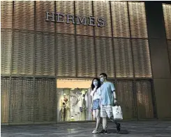  ?? Picture: Getty Images ?? A couple pass a Hermes store in Wuhan, China. Pent-up spending was seen in China as early as last April as the government began easing Covid restrictio­ns.