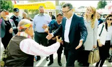  ??  ?? Prime Minister Tufan Erhürman being welcomed by a stall holder in Hisarköy. Right, a man selling asparagus at the Hisarköy festival.