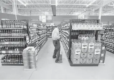  ?? Steve Gonzales photos / Houston Chronicle ?? Glazer’s sales representa­tive Greg Daniels stocks wine in the H-E-B Clear Lake Marketplac­e. The store’s 350 employees have spent the past two weeks stocking and prepping the aisles for opening day.