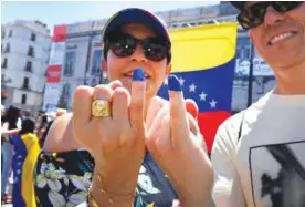  ??  ?? MADRID: Two Venezuelan residents in Madrid, show their little fingers stained with ink after voting during a symbolic plebiscite on President Maduro’s project of a future constituen­t assembly, called by the Venezuelan opposition and held at the Puerta...