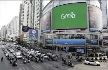  ?? PHOTO: EPA-EFE ?? Vehicles transit next to a large-scale screen displaying a logo of Grab (formerly GrabTaxi), a taxi hire mobile phone app. Toyota announced in March that it would invest $1 billion in the ride-hailing company.