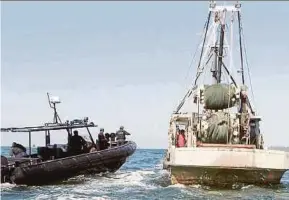  ??  ?? Security personnel inspecting a fishing vessel in the waters off Sandakan.