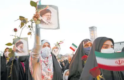  ?? Photos / AP ?? Supporters of Ebrahim Raisi hold placards with his face aloft.