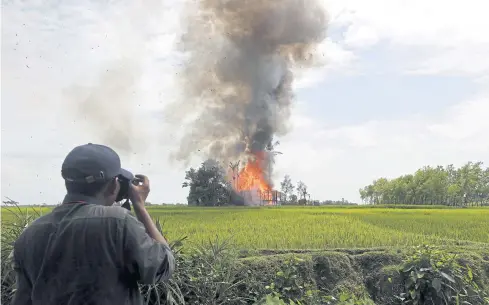  ?? EPA ?? A journalist takes photos of a burning house at a village in Rakhine state in September last year. As Rakhine is off-limits, most media stories from there are done as part of tours set by the state.