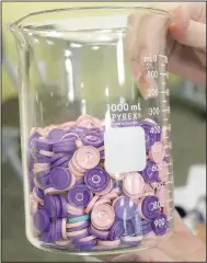  ?? (NWA Democrat-Gazette/Keith Bryant) ?? Pharmacist Karen Bond holds a beaker half-full of caps from covid-19 vaccine vials administer­ed during clinics hosted by Cornerston­e Pharmacy. Each vial contains half a dozen doses of the vaccine.