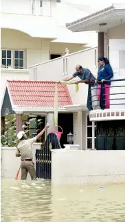  ??  ?? Karnataka fire and emergency service personnel rescue people and supply essentials to a marooned family in the Kodichikka­nhalli area of Bengaluru on Friday.