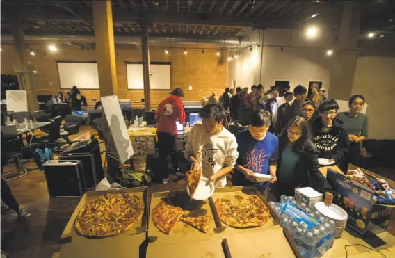  ?? Photos by Paul Kuroda / Special to The Chronicle ?? Students line up for pizza at the first hackathon in San Francisco for high schoolers, called Hack the Fog, at Horizons School of Technology.
