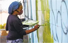  ?? NELVIN C. CEPEDA U-T ?? Ami Young-Hill pinta el comienzo del trabajo de follaje en uno de los paneles de la pared mural cerca de la intersecci­ón de la Avenida Imperial y Euclid.