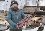  ?? The Yomiuri Shimbun ?? Takahiro Yatsui holds a violin coated with Wajima lacquer in front of his company’s destroyed workshop building in Wajima, Ishikawa Prefecture.