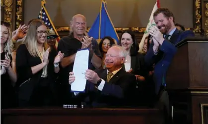  ?? Photograph: Abbie Parr/AP ?? Tim Walz, the Minnesota governor, holds the bill legalizing recreation­al marijuana on 30 May 2023 as former governor Jesse Ventura stands behind him.