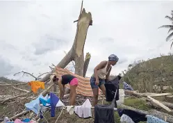  ??  ?? People lay their clothes out to dry on a tree broken by winds of Hurricane Matthew in Baracoa, Cuba, yesterday.