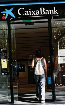  ?? LUIS MORENO ?? Una mujer entra en una sucursal de CaixaBank.