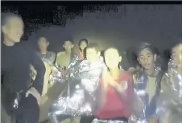  ?? THAI NAVY SEAL VIA AP ?? Thai boys are with Navy SEALs inside the cave. With heavy rains forecast to worsen flooding, authoritie­s say they might be forced to have them swim out through a narrow, underwater passage. The 13 are described as healthy and being looked after by...