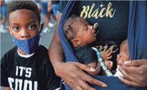  ?? JACQUELYN MARTIN/AP ?? Xavier Simmorins, 8, of Baltimore stands next to his brothers, 8-week-old twins Zuri and Zakai Simmorins, as they are held by their mother, Samara Simmorins, during a protest June 7 in Washington, D.C.