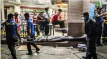  ??  ?? Funeral home workers carry away Edwin Mendoza Alon-Alon, 36, who was shot in the head outside a 7-Eleven store, in the Paranaque area of Manila.