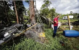  ?? BRUCE R. BENNETT / THE PALM BEACH POST ?? Lazaro Santos examines his property on Key Lime Boulevard in Loxahatche­e earlier this month after a tornado touched down. Santos said he didn’t get a tornado alert on his phone until after the twister had hit.