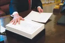  ?? DOUG MILLS / THE NEW YORK TIMES ?? President Donald Trump signs the tax reform bill Dec. 22, 2017, in the Oval Office of the White House. Nearly a year after the tax cuts took effect, economic growth has accelerate­d, but wage growth has not. Companies are buying back stock, and business investment is a mixed bag.