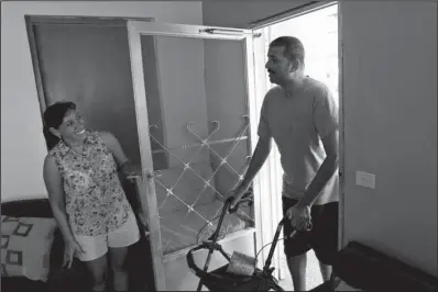  ??  ?? DEEP CUTS: Brenda Torres opens a screen door for her husband, Jose Gonzalez Ortiz, 42, who suffers from Lou Gehrig’s disease, Nov. 11 at their home in Arecibo, Puerto Rico. Puerto Rico’s public health care plan, which receives funding from Medicaid,...