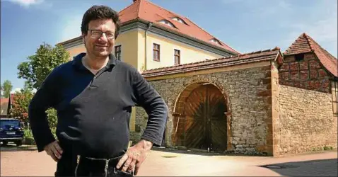  ??  ?? Johannes Fliegel vor dem Hof in Backleben. Unter zweifachem freskalem Kalkfarban­strich, Knottenbew­urf und mehrlagige­n Reinkalkpu­tzen findet sich eine  Zentimeter starke Dämmung aus Schilfrohr – und darunter Fachwerk. Das Dach rechts , Tür und Tor...