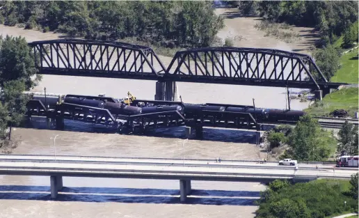  ?? Larry MACDOUGAL / THE CANADIAN PRESS ?? Rail cars loaded with flammable liquid derailed during a bridge collapse over the Bow River in Calgary.