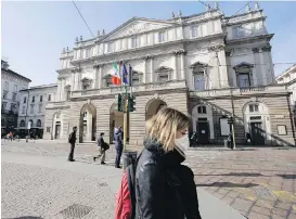  ??  ?? A woman wearing a sanitary mask walks past La Scala Opera house in Milan. There is not a single woman among the 20-member commission appointed to advise the government on Italy’s reopening.