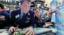  ?? [AP PHOTO] ?? Specialist­s Gregg Maloney, left, and Michael Pistillo work at their post near the close of trading Wednesday on the floor of the New York Stock Exchange.