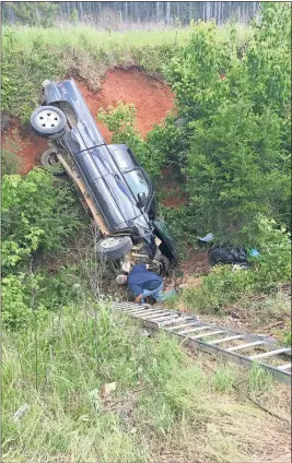  ?? Spencer Lahr / Rome News-Tribune ?? Lee Boatfield, of Lee’s Wrecker & Automotive, looks for a place to attach a cable on a Chevrolet Silverado that landed at the bottom of this embankment off U.S. 411.