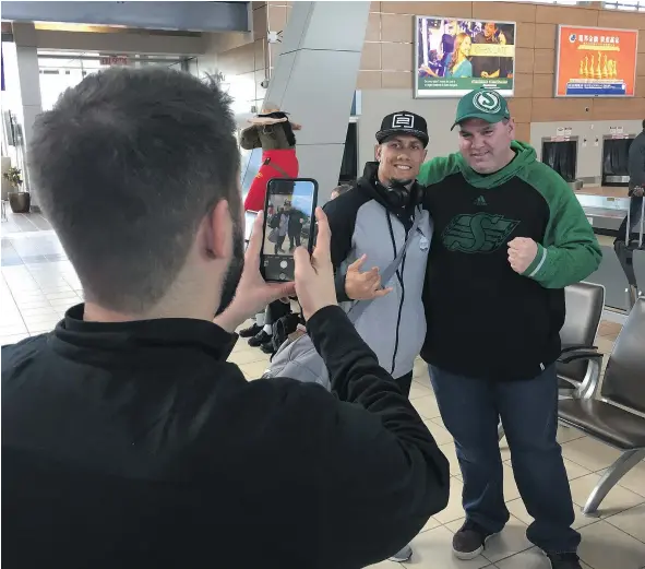  ?? — POSTMEDIA NEWS ?? Saskatchew­an Roughrider­s receiver Chad Owens, left, posed for a picture with a Roughrider­s fan at Regina Internatio­nal Airport Monday and said he was excited to be in town to experience the first CFL Week featuring 56 of the league’s biggest stars.