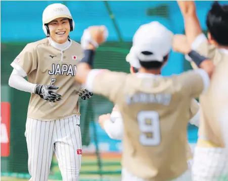  ?? KYODO NEWS VIA THE ASSOCIATED PRESS ?? Japan’s Saki Yamazaki, left, is greeted by teammates after hitting an inside-the-park home run Sunday against Canada in the women’s world softball championsh­ip semifinal in Chiba, Japan.