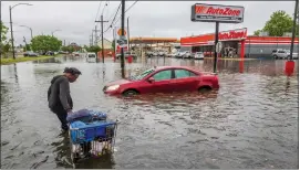  ?? CHRIS GRANGER/THE TIMES-PICAYUNE/THE NEW ORLEANS ADVOCATE VIA THE ASSOCIATED PRESS ?? People carry their belongings down a flooded Broad Street in New Orleans, during a severe rainstorm on Wednesday.