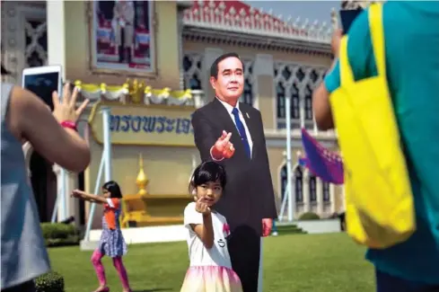  ?? AFP ?? A girl makes a hand gesture next to a cardboard cutout of Thai Prime Minister Prayuth Chan-O-Cha at Government House during Children’s Day in Bangkok on January 13 last year.