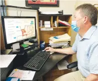  ?? (AP photo/David A. Lieb) ?? On Tuesday, Tim Corbin, administra­tor of Truman Lake Manor nursing home, looks at a map showing COVID-19 transmissi­on levels in Lowry, Mo.