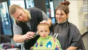  ??  ?? Volunteer Jewel Smith of Searcy Beauty College gives Luke Russell, 2, a haircut as he sits with his mother, Laura Oxford.