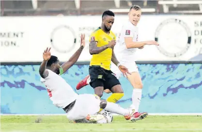 ?? ?? Jamaica’s Junior Flemmings (centre) is tackled by Doneil Henry (left) and Alistair Johnston of Canada during yesterday’s Concacaf World Cup qualifying match at the National Stadium.