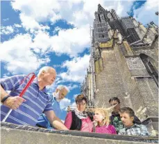  ?? FOTO: FELIX KÄSTLE ?? Seit Jahren engagiert er sich in Ulm: der blinde Stadtführe­r Hartmut Dorow (links) mit Touristen am Fuß des Münsters.