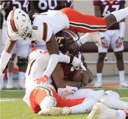  ?? AP ?? Miami defenders Sam Brooks Jr. ( top) and Jaelan Phillips ( bottom) tackle Virginia Tech quarterbac­k Hendon Hooker on Saturday.