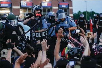  ?? Associated Press ?? ■ A police officer gestures at protesters who have been detained pending arrest Sunday on South Washington Street in Minneapoli­s.