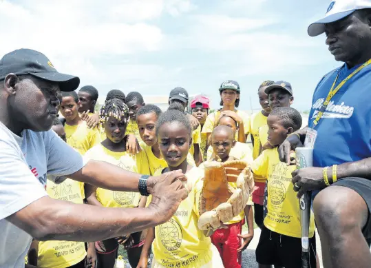  ?? FILE ?? Andrew Dixon (right), founder and president of the Andrew Dixon Foundation, and coach Leon Taylor (left), show youngsters catching techniques during a baseball clinic at the Breezy Castle field in central Kingston on Tuesday, July 30, 2013.