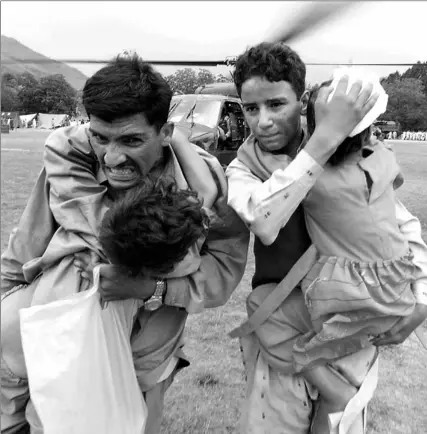  ?? JEWEL SAMAD / AFP / GETTY IMAGES ?? Volunteers carry injured children who are to be evacuated by a U.S. helicopter from hard-hit Muzaffarab­ad, Pakistan, yesterday.