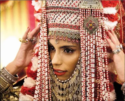  ?? The New York Times/MALIN FEZEHAI ?? Bride Meyrav Yehud adjusts the final accessorie­s of her henna outfit during a henna ceremony at the Yemeni Heritage Center in Rosh HaAyin, Israel. Pre-wedding henna ceremonies have regained popularity in Israel’s Jewish Yemenite community, an expression of ethnic pride in their heritage and traditions.