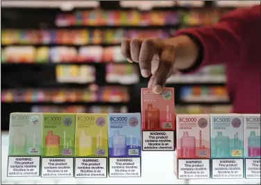  ?? (AP/Rebecca Blackwell) ?? An employee displays some of the varieties of disposable electronic cigarette devices manufactur­ed by EB Design, formerly known as Elf Bar, at Vapes N Smoke in Pinecrest, Fla., late last month.