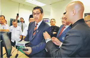  ?? — Gambar Bernama ?? TANGANI ANCAMAN: Abu Bakar (dua kanan) mendengar taklimat tentang alat yang dibangunka­n CyberSecur­ity Malaysia bagi menangani ancaman perisian jahat selepas merasmikan Makmal Satelit ‘Coordinate­d Malware Eradicatio­n and Remediatio­n Project’ (CMERP) di...