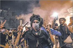  ?? GETTY-AFP ?? A protester wears tear gas canisters on his fingers and gives the victory sign during anti-government demonstrat­ions late Monday in the city of Karbala, south of Baghdad.