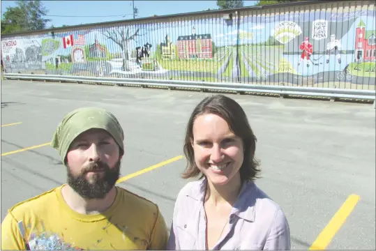  ?? MATTHEW MCCULLY ?? Township artist Trevor Mckinven and Stanstead Youth Centre Coordinato­r Clea Corman standing in front of 150-foot illustrati­on of the past, present and possible future of Stanstead