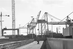  ??  ?? A man walks along a walkway at the port in Barcelona, Spain October 16. Spain’s government announced it was cutting its forecast from 2.6 per cent to 2.3 per cent economic growth next year, saying the political crisis in Catalonia was creating...