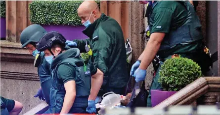  ??  ?? Aftermath: Medical staff carry a man from the hotel where six people were injured yesterday
